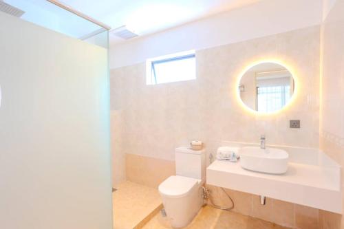 a bathroom with a toilet and a sink and a mirror at Suntai Villa, Beachfront Suites in Kampong Si Ginting