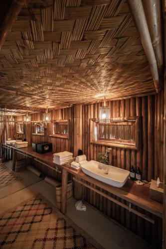 a bathroom with a tub and a wooden wall at The Beach House Ocam Ocam in Busuanga