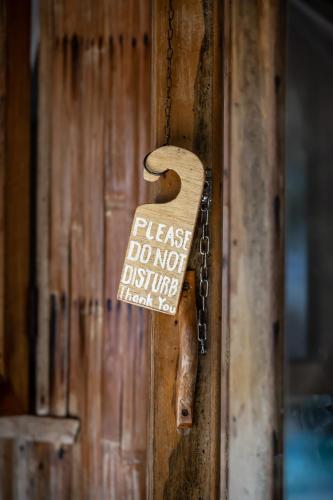 a wooden door handle with a sign on it at The Beach House Ocam Ocam in Busuanga