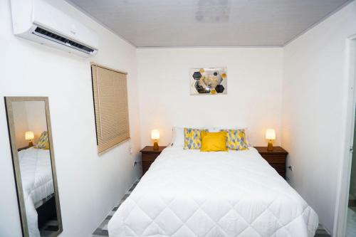 Schlafzimmer mit einem weißen Bett und einem Spiegel in der Unterkunft Casa Nella in Tamarindo
