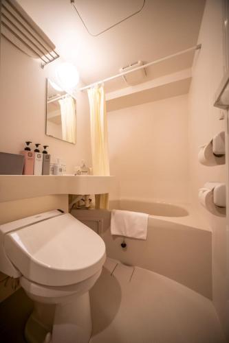 a white bathroom with a toilet and a sink at JA Hotel Namba-SOUTH難波南 in Osaka