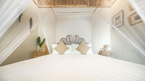 a bedroom with a large white bed with pillows at The Beach House Ocam Ocam in Busuanga
