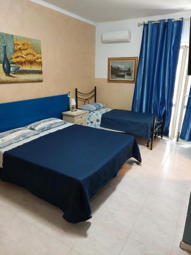 1 dormitorio con 2 camas y cortinas azules en Oasi Del Relax, en Civitavecchia