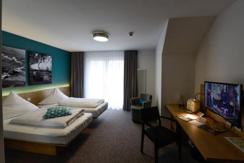 a hotel room with two beds and a desk at Hotel Am Markt in Ennigerloh