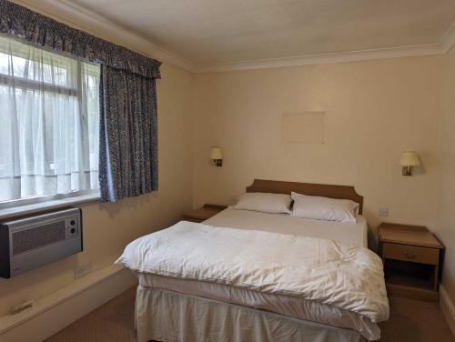 1 dormitorio con 1 cama, TV y ventana en OYO The Rivenhall Hotel, en Witham