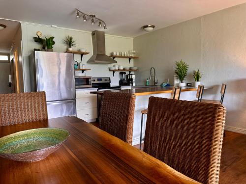 North Shore of Maui - 2bd-2bath في بايا: مطبخ مع طاولة خشبية مع كراسي وطاولة مطبخ