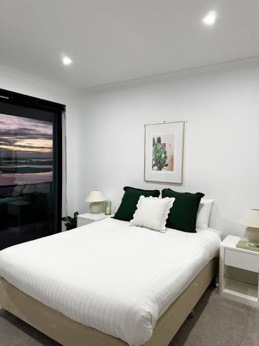 a white bedroom with a large bed and a window at Sheer Pleasure Accommodation in Smithton