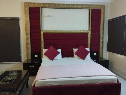 a bedroom with a large bed with a red headboard at Hotel Shelton in Karachi