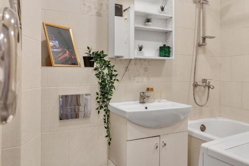 Tower View Apartment في فيلنيوس: حمام أبيض مع حوض ومرآة