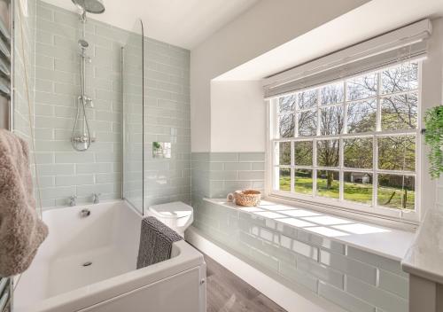 a bathroom with a tub and a toilet and a window at Churchtown Cottage in Blisland