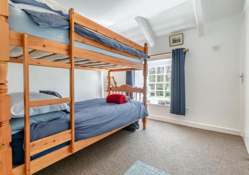 a bedroom with two bunk beds and a window at Churchtown Cottage in Blisland