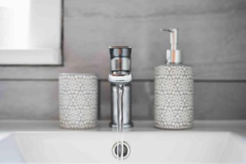 a bathroom sink with a faucet and two cups on a counter at Beautiful 4 Bedroom House by the River in Southampton