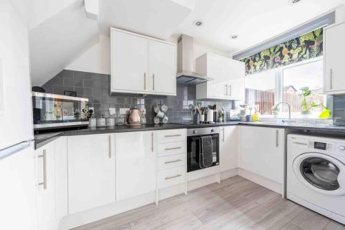 a kitchen with white cabinets and a washer and dryer at Beautiful 4 Bedroom House by the River in Southampton