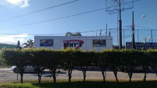 Dinys Motel (Adults Only) في برايا جراندي: مبنى عليه لافتة على شكل نمر جبلي بجوار صف من الأشجار