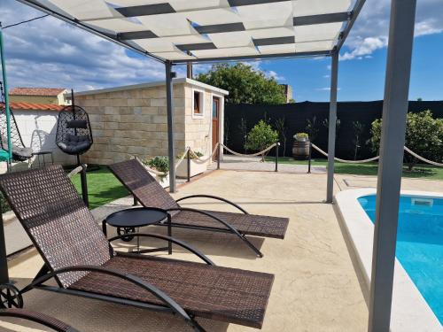 eine Terrasse mit 2 Stühlen und einem Pool in der Unterkunft Holiday Home near Trogir in Kaštel Štafilić