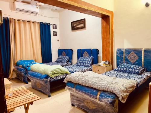 Habitación con 3 camas y mesa. en Islamabad guest house, en Islamabad