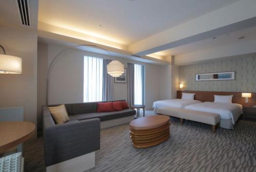 um quarto de hotel com uma cama e um sofá em Odakyu Hotel Century Sagami Ono em Sagamihara