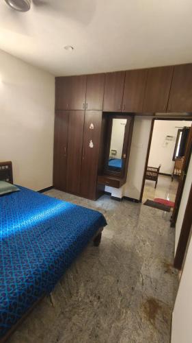 a bedroom with a blue bed and wooden cabinets at HACIENDA APARTMENT in Chennai