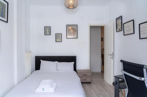 a bedroom with a white bed and some pictures on the wall at Kosmos Service Apartment Near Saint Dimitrious Church in Thessaloniki