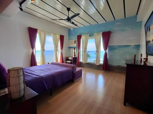 CatmonにあるKums Vacation Beach House in Catmonの窓付きの部屋に紫色のベッドが備わるベッドルーム1室が備わります。