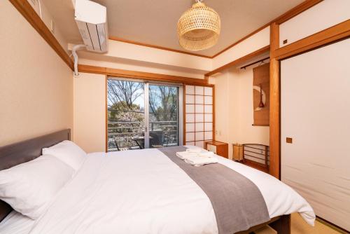 een slaapkamer met een groot wit bed en een raam bij CoCoHouse Asakusa - SkyTree View, 72㎡ in Tokyo