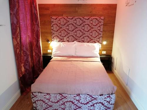 a bed with a red headboard in a room at Nest of love in San Damiano dʼAsti