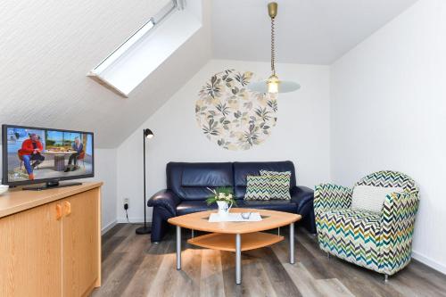 a living room with a couch and a table and a tv at Haus Strandlooper in Neuharlingersiel