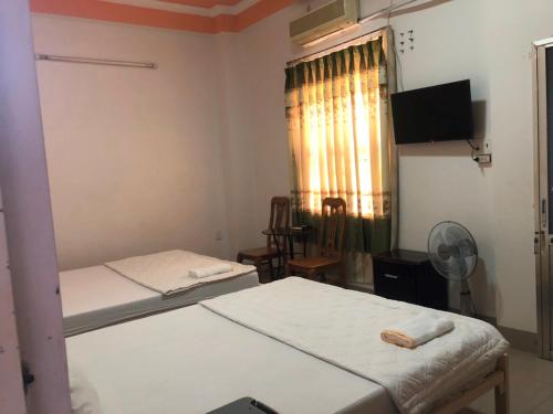 Habitación con 2 camas y ventana con ventilador. en Nam Dương 3 Hotel en Phan Rang