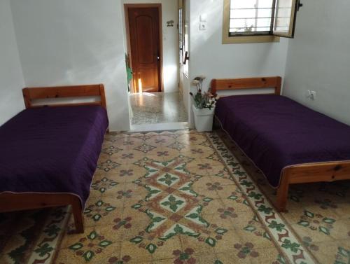 two beds in a room with a rug at Fay's House in Mesargos