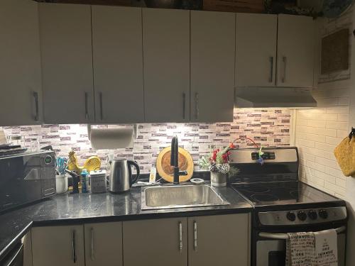 a kitchen with white cabinets and a sink and a stove at Luxury one bedroom condo in Kitchener