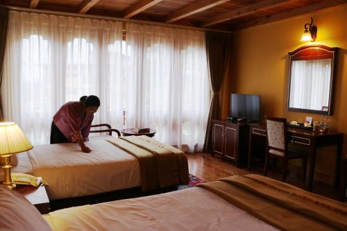a woman making a bed in a hotel room at Tiger's Nest Resort - Best Resort In Paro in Paro