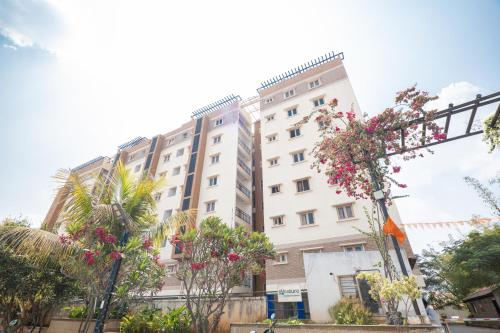 a large white building with flowers in front of it at Guesture Stays - Dwellington, Electronics City Phase 2 in Bengaluru