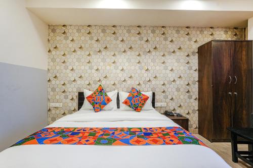 a bedroom with a white bed with colorful pillows at FabExpress 24 Plus in Bangalore