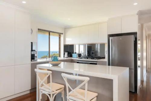a kitchen with a large white island with two stools at Hallett Cove Hideaway By Host Solutions in Halletts Cove