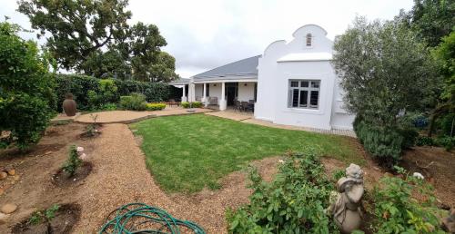 a yard with a white house with a garden at Journey Guesthouse in Riversdale