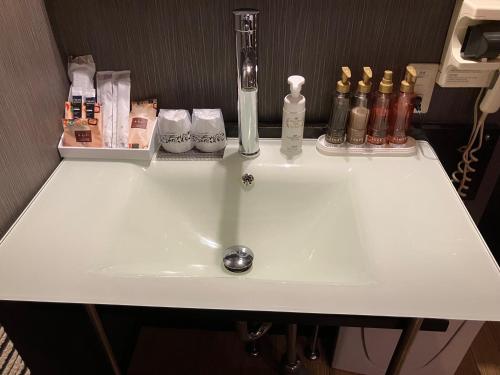 X ホテル（レジャーホテル） في Sayama: وجود مغسلة بيضاء في الحمام وزجاجات عليها