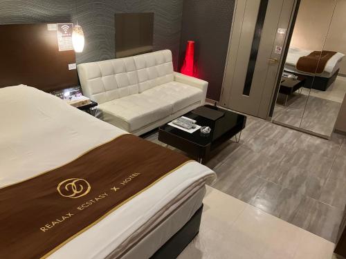 um quarto de hotel com uma cama e um sofá em X Hotel - Adult Only- em Sayama