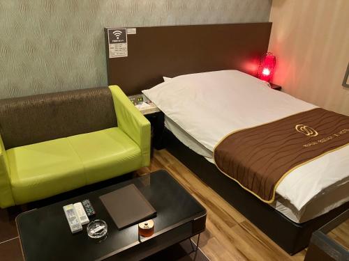 a room with a bed and a chair and a table at X Hotel - Adult Only- in Sayama
