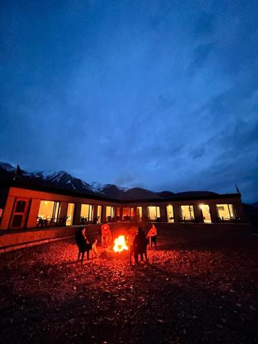 a group of people standing around a fire in front of a building at Mystic Pangong in Spangmik