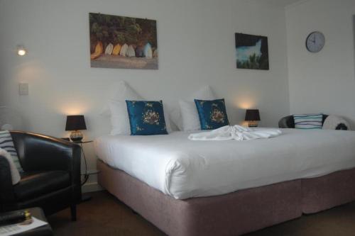 um quarto com uma grande cama branca com almofadas azuis em Rotorua Motel em Rotorua