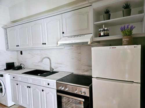 La cuisine blanche est équipée d'un évier et d'un réfrigérateur. dans l'établissement Paradosi Apartments, à Igoumenítsa