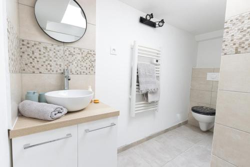 une salle de bain blanche avec un lavabo et un miroir dans l'établissement Cocon à deux minutes de la mer., à Propriano