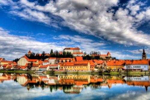 einen Blick auf eine Stadt mit ihrer Reflexion im Wasser in der Unterkunft Rooms Hiša Divino in Ptuj