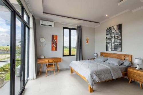 een slaapkamer met een bed, een bureau en ramen bij D`Arka Guesthouse No 3 close to beach in Canggu