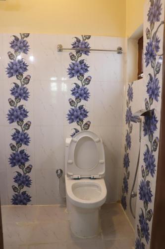 a bathroom with a toilet with blue flowers on the wall at Hotel Flycatcher Chitwan in Sauraha