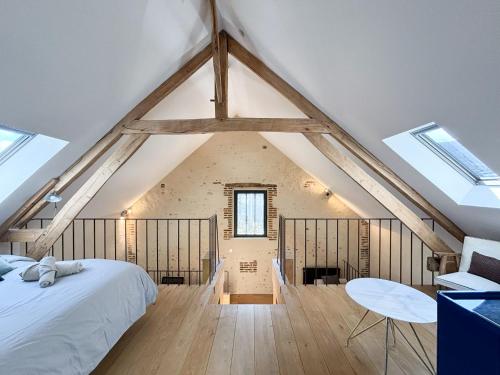 een slaapkamer op zolder met een bed en een tafel bij Superbe Grange et son bain nordique, endroit paisible du Perche in Soligny-la-Trappe