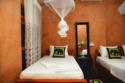 a bedroom with two beds and a mirror at Akash Treehouse in Sigiriya