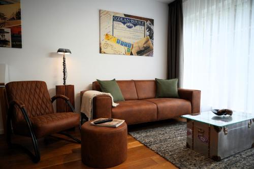 a living room with a brown couch and a chair at The Berlin Getaway / 80qm in Berlin's Historic Diplomatic Quarter in Berlin