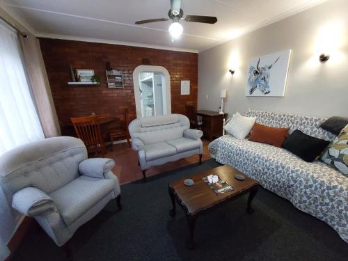 Una sala de estar con sofás y sillas y una mesa. en Coral Cottage, en Hilton