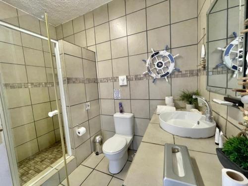 a bathroom with a toilet and a sink and a shower at Casa Do Mar Guest House in Praia do Tofo